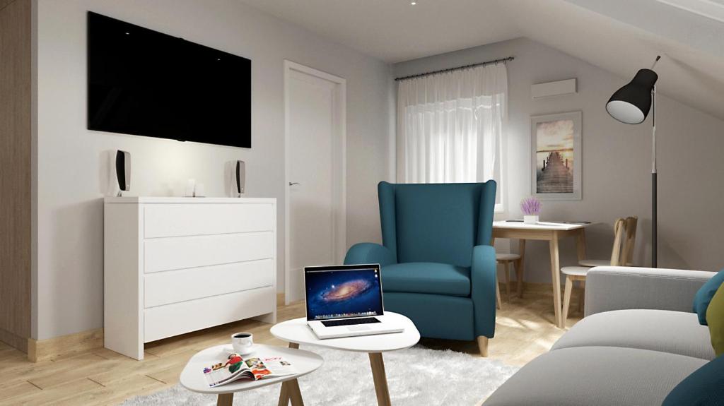 uma sala de estar com uma cadeira azul e um computador portátil sobre uma mesa em METRAK Apartamenty Darlowo em Darłowo