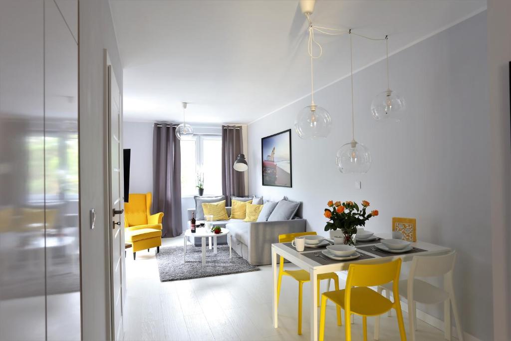 uma sala de estar com uma mesa e cadeiras amarelas em Apartamentowiec Dwie Sosny em Ustronie Morskie