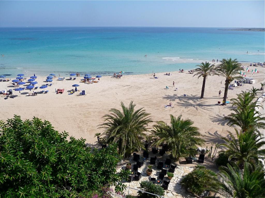 a beach with people and palm trees and the ocean at Hotel Capo San Vito by Geocharme in San Vito lo Capo