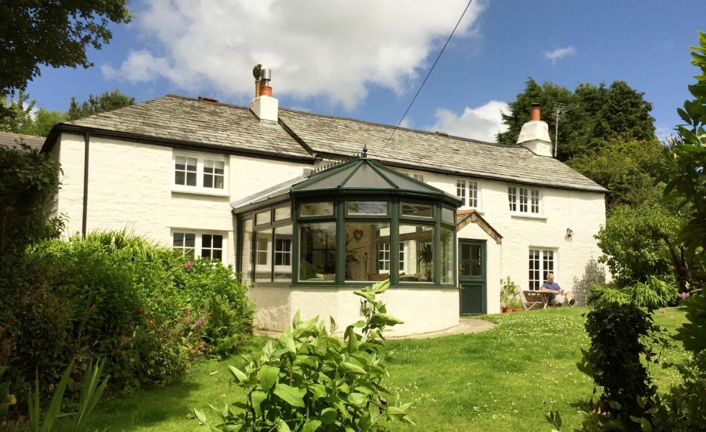 a white house with a conservatory in the yard at Blisland Cottage in Blisland