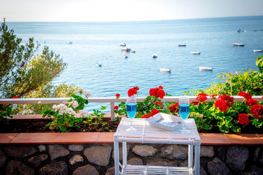 a table with red flowers and a view of the water at Blue eyes in Nerano