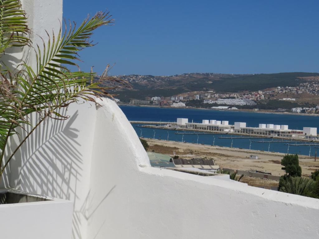 a view of a harbor from a white wall with a plant at Riad Arous Chamel in Tangier