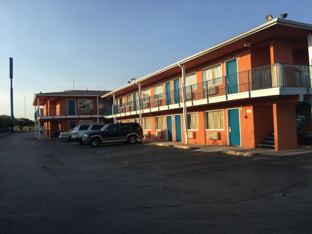 a building with cars parked in a parking lot at Relax Inn Forth Worth in Fort Worth