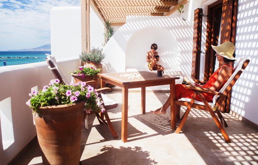 a woman sitting at a table on a balcony at Apartment Kalypso in Agia Anna Naxos