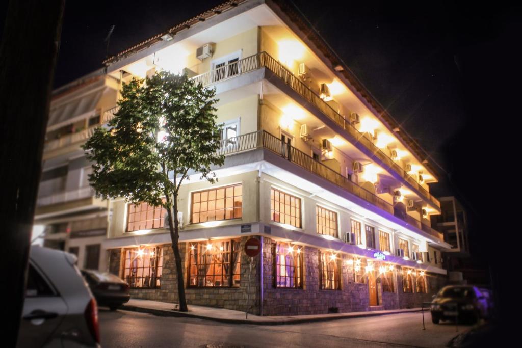 Un grand bâtiment blanc avec des lumières allumées la nuit dans l'établissement Hotel Galaxy, à Kalambaka