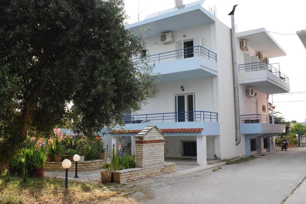 a white building with balconies and a tree at Lydia Rooms & Studios in Preveza