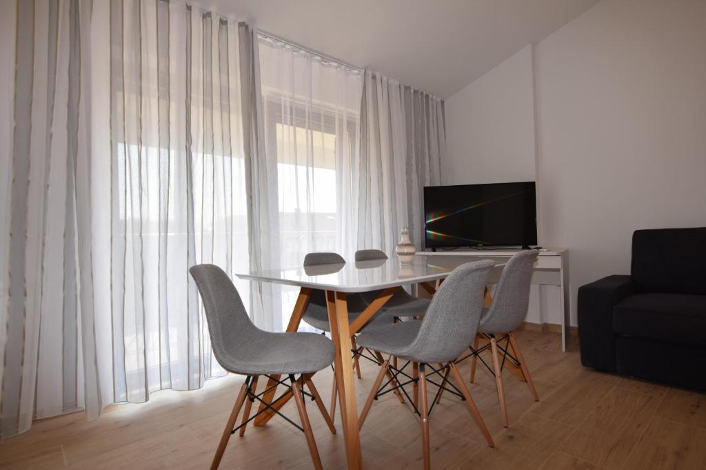 ein Wohnzimmer mit einem Tisch, Stühlen und einem TV in der Unterkunft Apartments Pavić Valbandon in Fažana