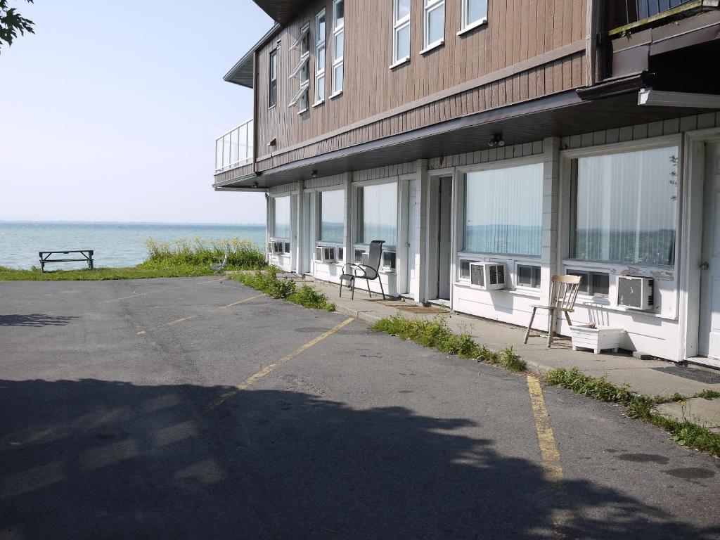 a building with a parking lot next to the ocean at Motel Rive Du Lac in Saint-Zotique