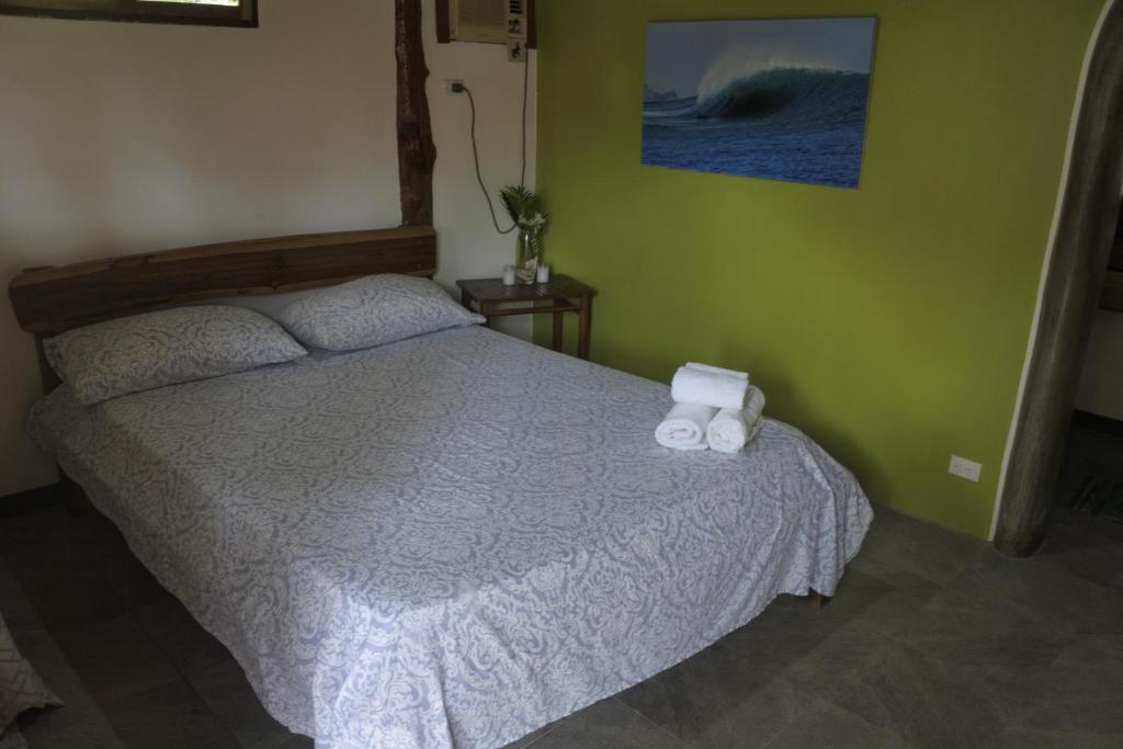 a bedroom with a bed with two towels on it at Wild Waves Surf-House in Popoyo