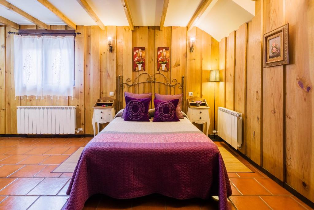 a bedroom with a large bed with purple pillows at Apartamentos Rurales L´Abiseu in Caboalles de Abajo