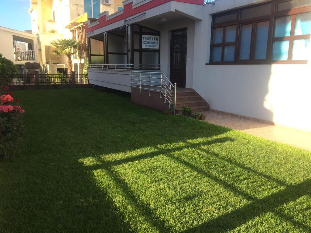 ein Haus mit grünem Rasen davor in der Unterkunft Apartmani MN Velika Plaza Stoj in Ulcinj