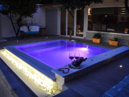 a swimming pool with purple lights in a backyard at Alla corte di Re Federico in Lamezia Terme