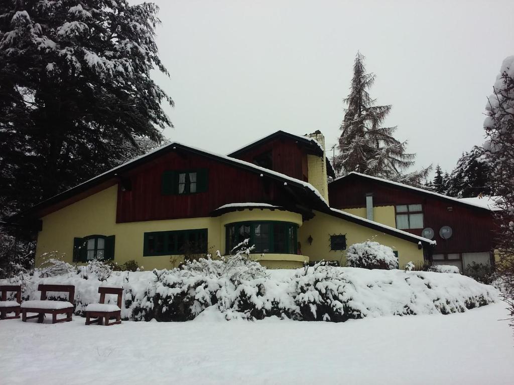 een huis bedekt met sneeuw met bankjes ervoor bij La Posada del Trebol in Bariloche