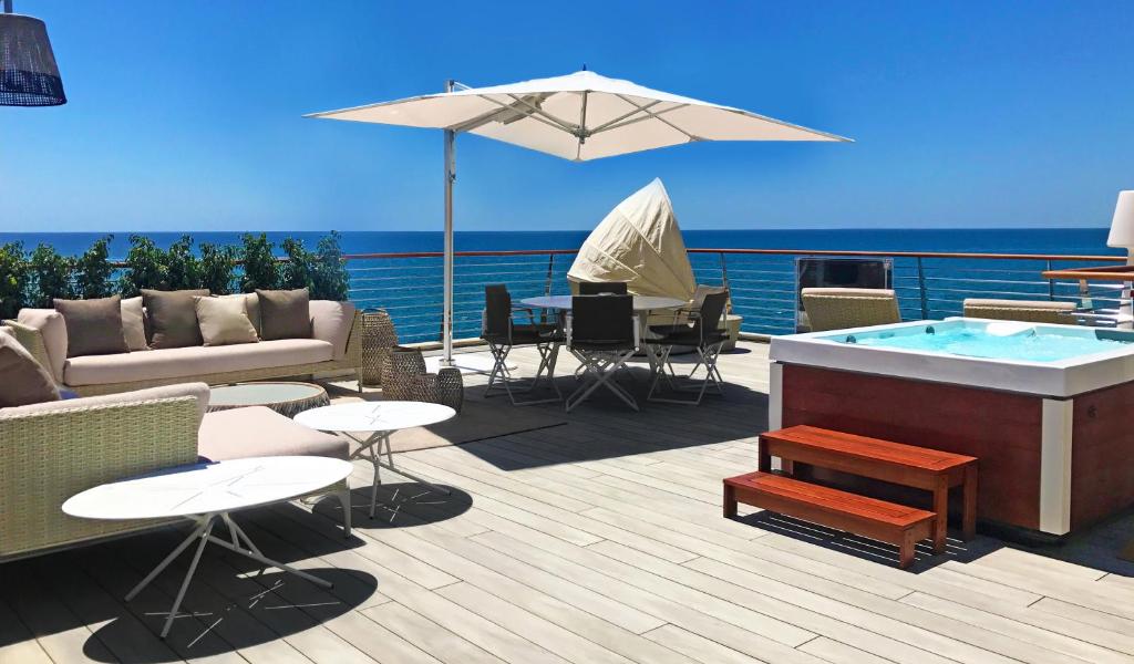 una terraza con bañera de hidromasaje, mesas y sillas en Seaside Villa, en Alicante