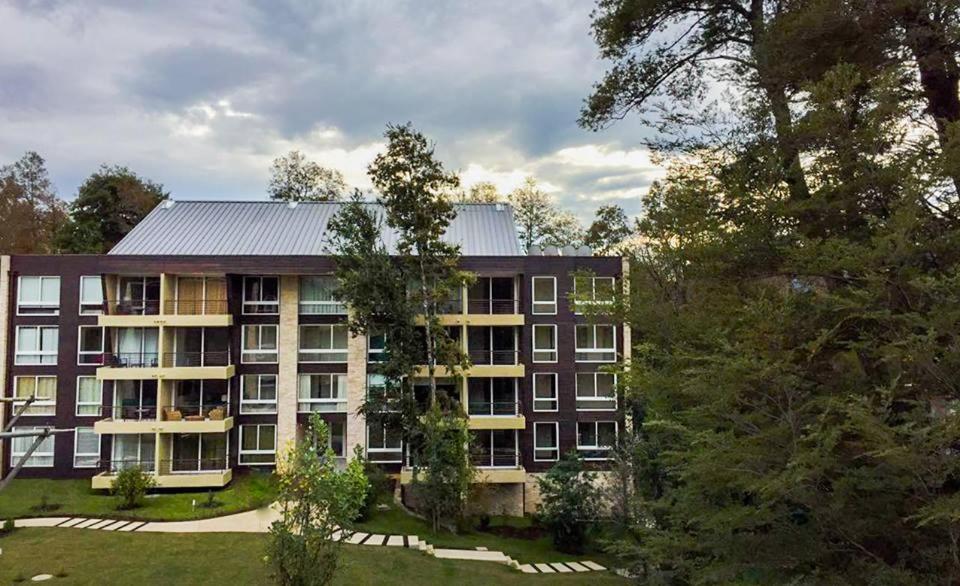 Un edificio de apartamentos con árboles en frente. en Departamento Familiar, en Pucón