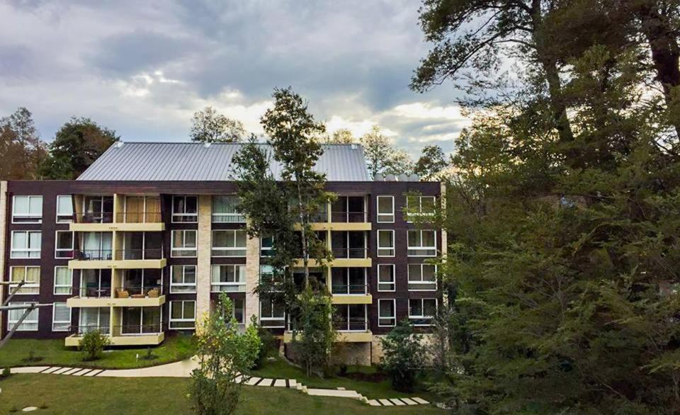 un edificio de apartamentos con árboles delante de él en Departamento Familiar, en Pucón