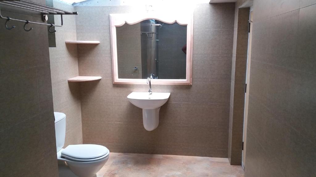 a bathroom with a sink and a toilet and a mirror at Raj Estate Stay in Madikeri