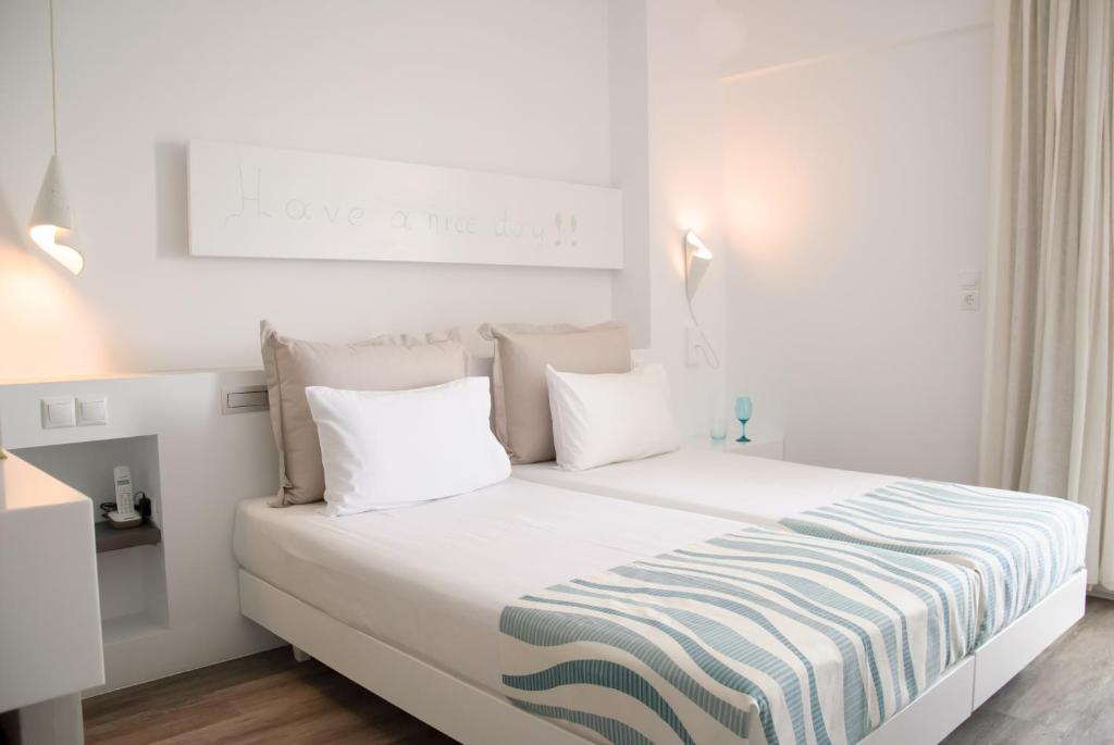 a white bedroom with a bed with a striped blanket at Kouros Seasight Hotel in Pythagoreio
