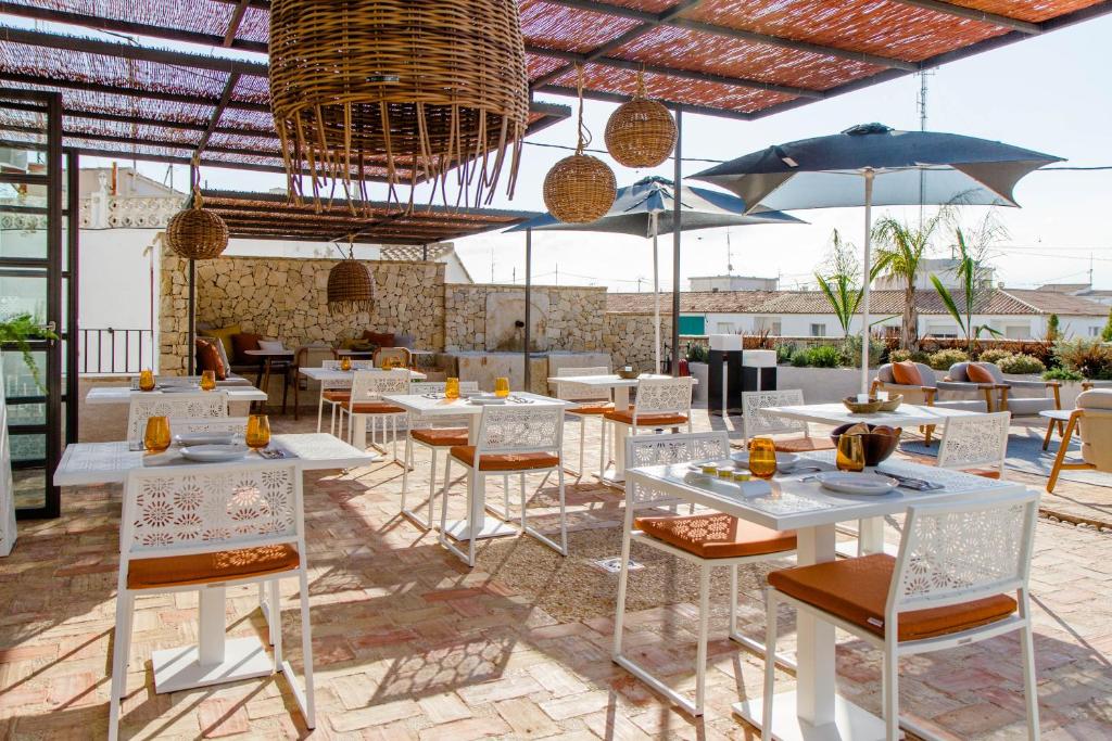 a restaurant with white tables and chairs and umbrellas at La Serena Boutique Hotel & Wellness - Altea in Altea