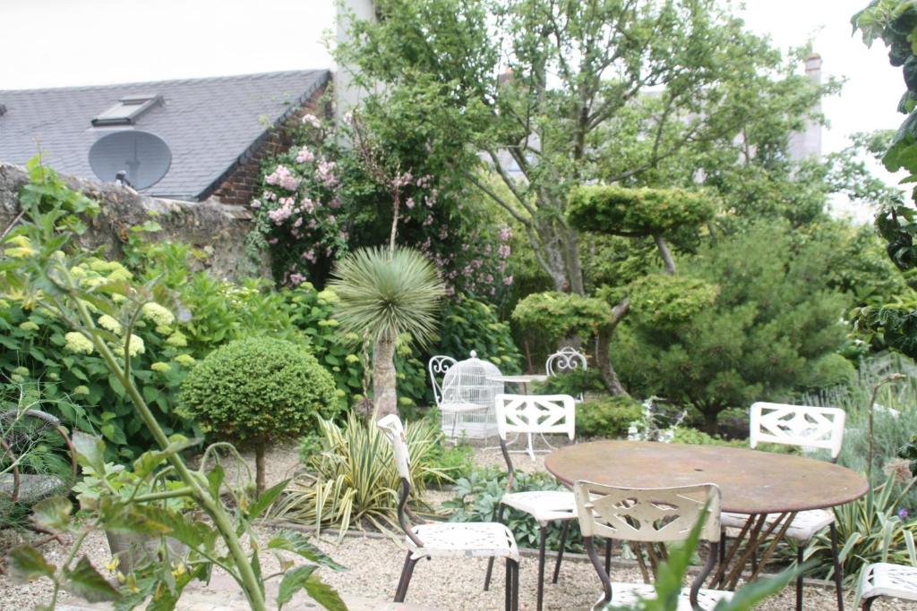 un patio con mesa y sillas en un jardín en Logis Saint-Léonard, en Honfleur