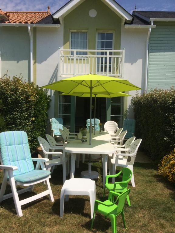 タルモンにある3 bedrooms Holiday Home Golf Resort Port-Bourgenayの家の前にテーブルと椅子、傘