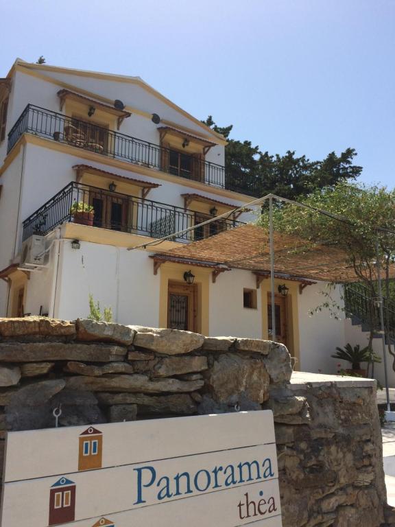 a building behind a stone wall with a sign in front at Panorama Thea in Symi