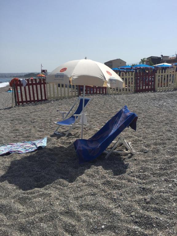 two chairs and an umbrella on a beach at Casa Vacanze Samira in Fondachello