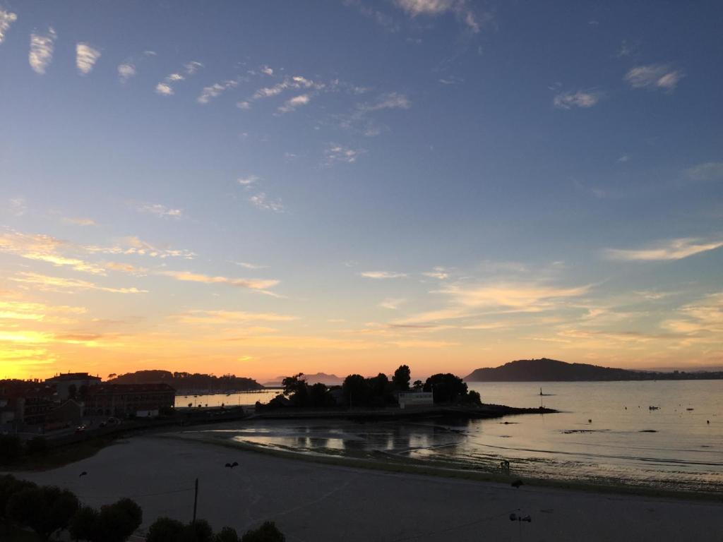 バイヨーナにあるPiso 1º línea Playa Ladeira Baionaの夕日を背景にビーチの景色を望む客室です。