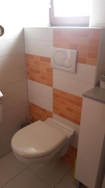 ein Badezimmer mit einem weißen WC und orangefarbenen Fliesen in der Unterkunft Ferienwohnung Claudia & Dino in Lahnstein