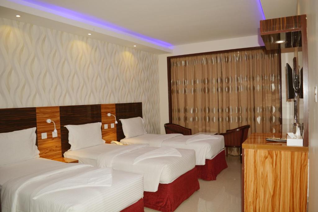 a hotel room with four beds in a row at Zagy Hotel in Dubai