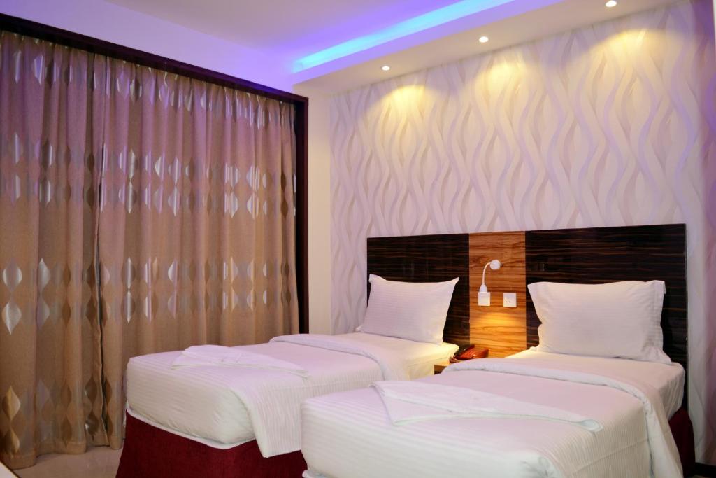 two beds in a hotel room with purple lighting at Zagy Hotel in Dubai