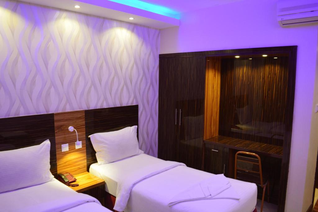 two beds in a room with purple lighting at Zagy Hotel in Dubai