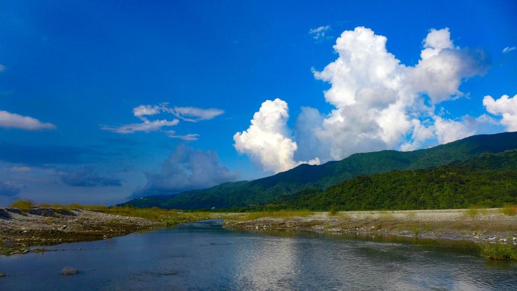 um rio com montanhas e nuvens no céu em Huxi B&B em Jian