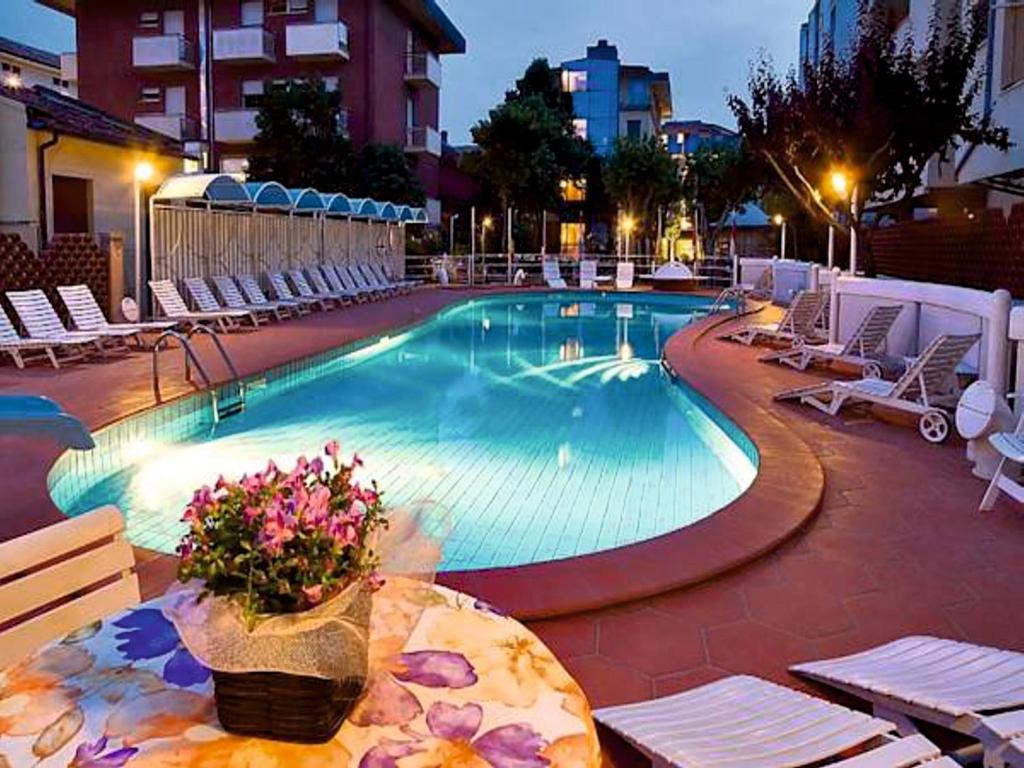 una gran piscina con sillas y un jarrón de flores en Hotel Rosalba - Valentini Family Village, en Bellaria-Igea Marina