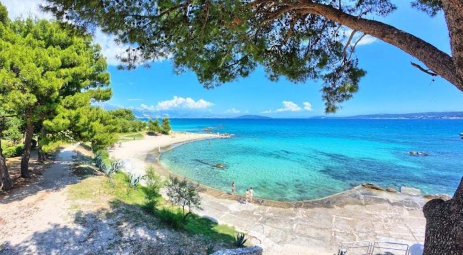 een uitzicht op een strand met bomen en het water bij By The Sea in Kaštela