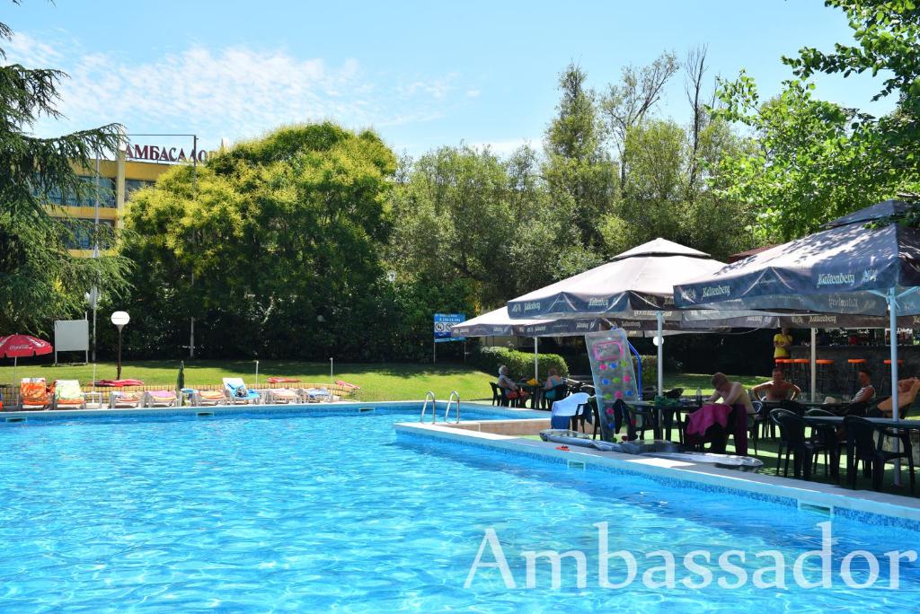 una piscina con mesas y sombrillas junto a un edificio en Hotel Ambassador - Free Parking en Golden Sands