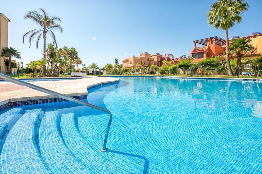 a swimming pool at a resort with palm trees and houses at Ático Playa de los Álamos in Torremolinos