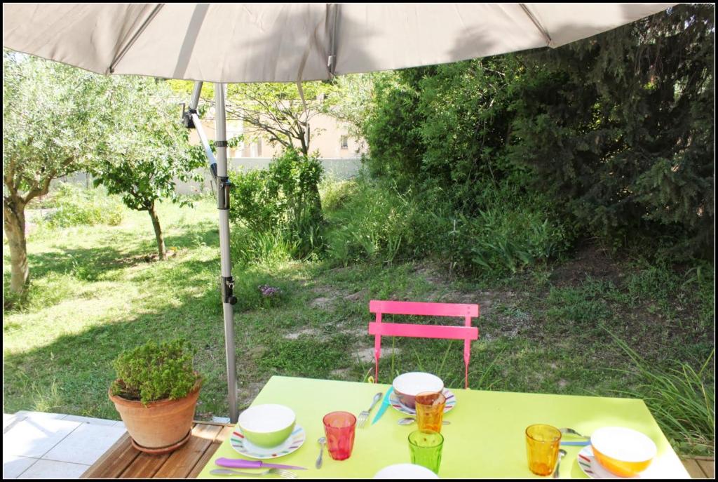 una mesa con sombrilla y una silla rosa en Gîte du Fenouil, en Lézignan-Corbières