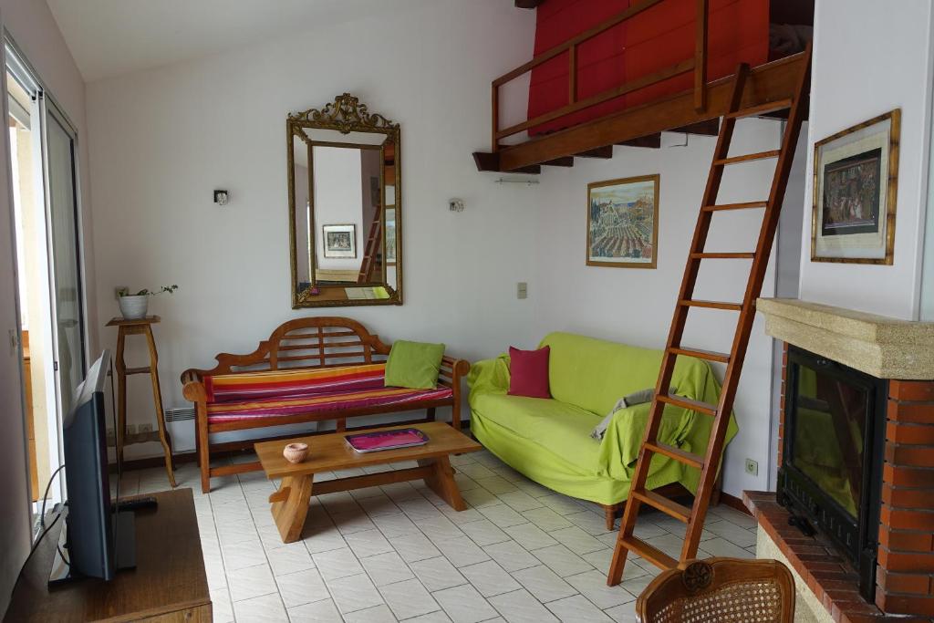 sala de estar con sofá verde y escalera en Gîte du Fenouil, en Lézignan-Corbières