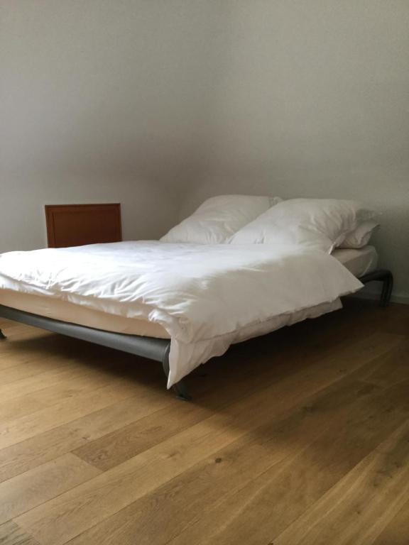 - un lit avec des draps et des oreillers blancs sur du parquet dans l'établissement Apartment am Klinikum, à Cassel