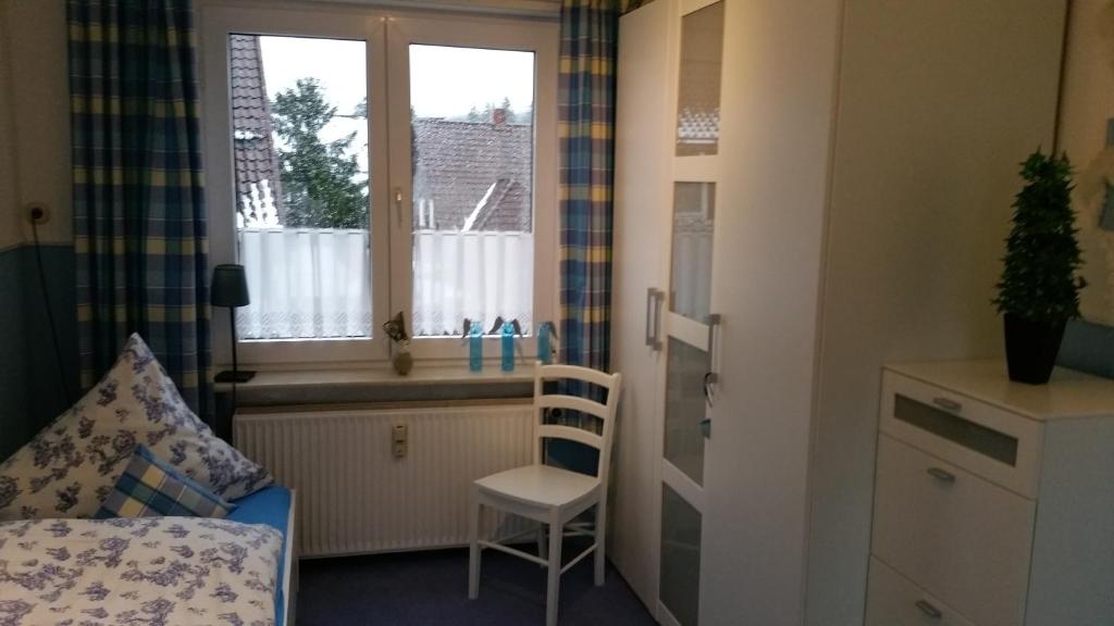 um quarto com uma cama, uma janela e uma cadeira em Haus Isabelle OG em Sankt Andreasberg