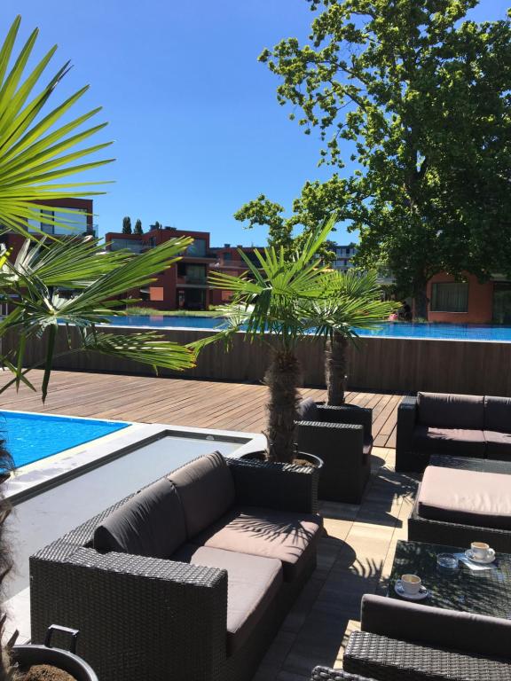 un patio con sofá y sillas junto a la piscina en Butique Apartman Grand, en Balatonlelle