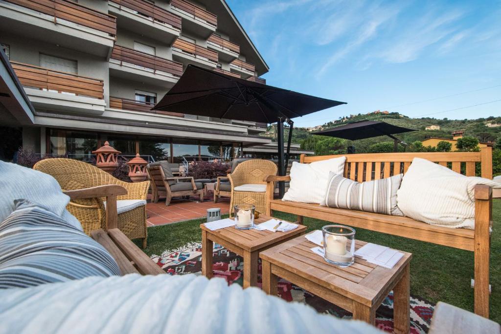 a patio with couches and tables and an umbrella at Hotel Michelangelo & Day SPA in Montecatini Terme