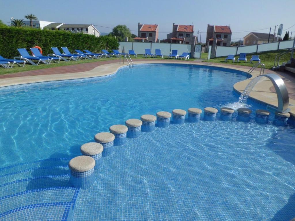 a large swimming pool with blue chairs in a resort at Hotel Brisa in A Lanzada