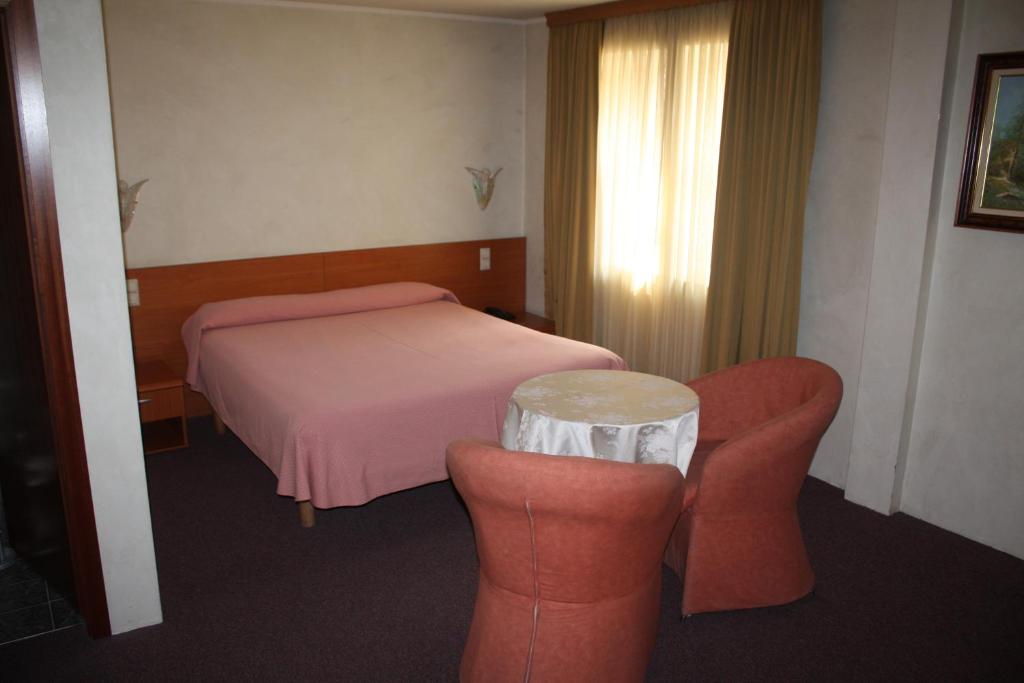 a bedroom with a bed and two chairs and a table at Auberge Gaglioti in Luxembourg