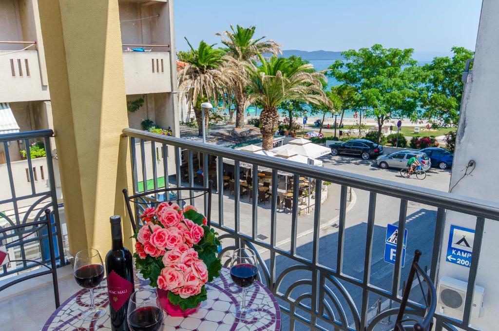 - une table avec des fleurs et des verres à vin sur le balcon dans l'établissement Apartments Keli, à Kaštela