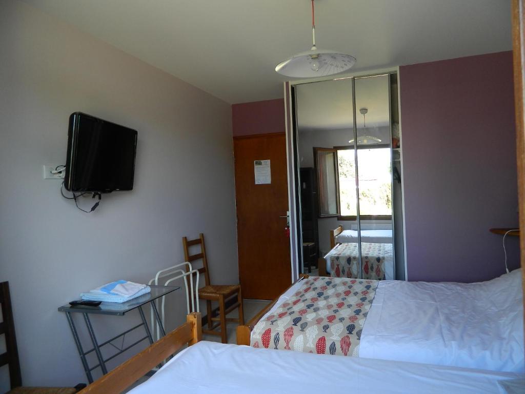 ein Schlafzimmer mit einem Bett und einem TV an der Wand in der Unterkunft Chambre d'Hôtes Les 3 Moulins in Cozes
