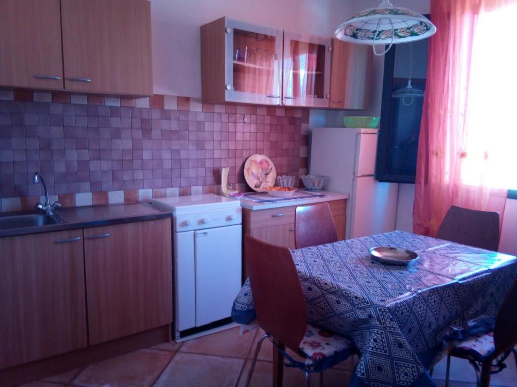 a kitchen with a table and a table and a sink at SA DOMU SARDA CASE VACANZe in Piscinas