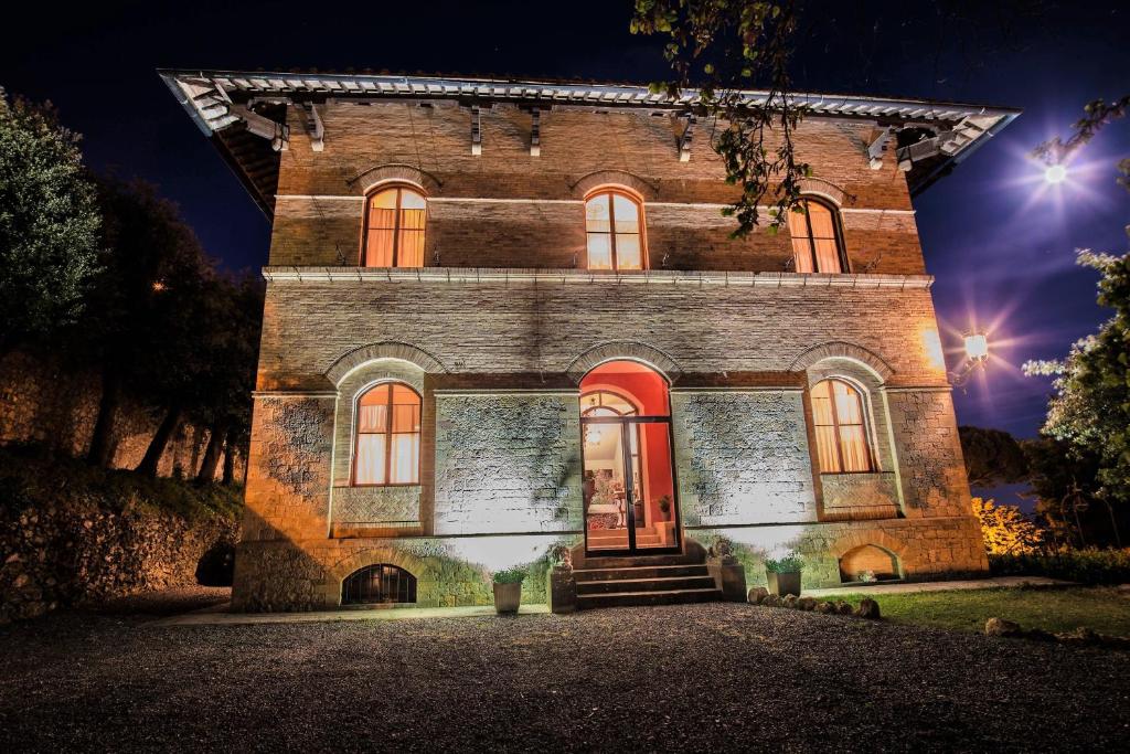 a large brick house with a red door at night at Appartamenti Villa Mascagni in Volterra