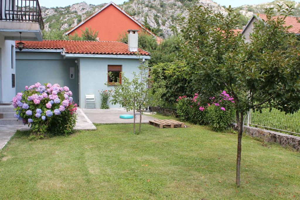 a yard with a house with flowers and a bench at Guesthouse Vujacic in Cetinje
